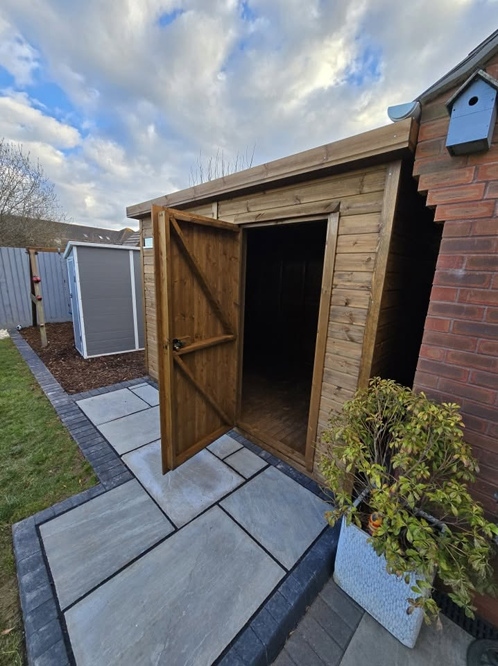 Timber garden shed with a newly laid grey stone path