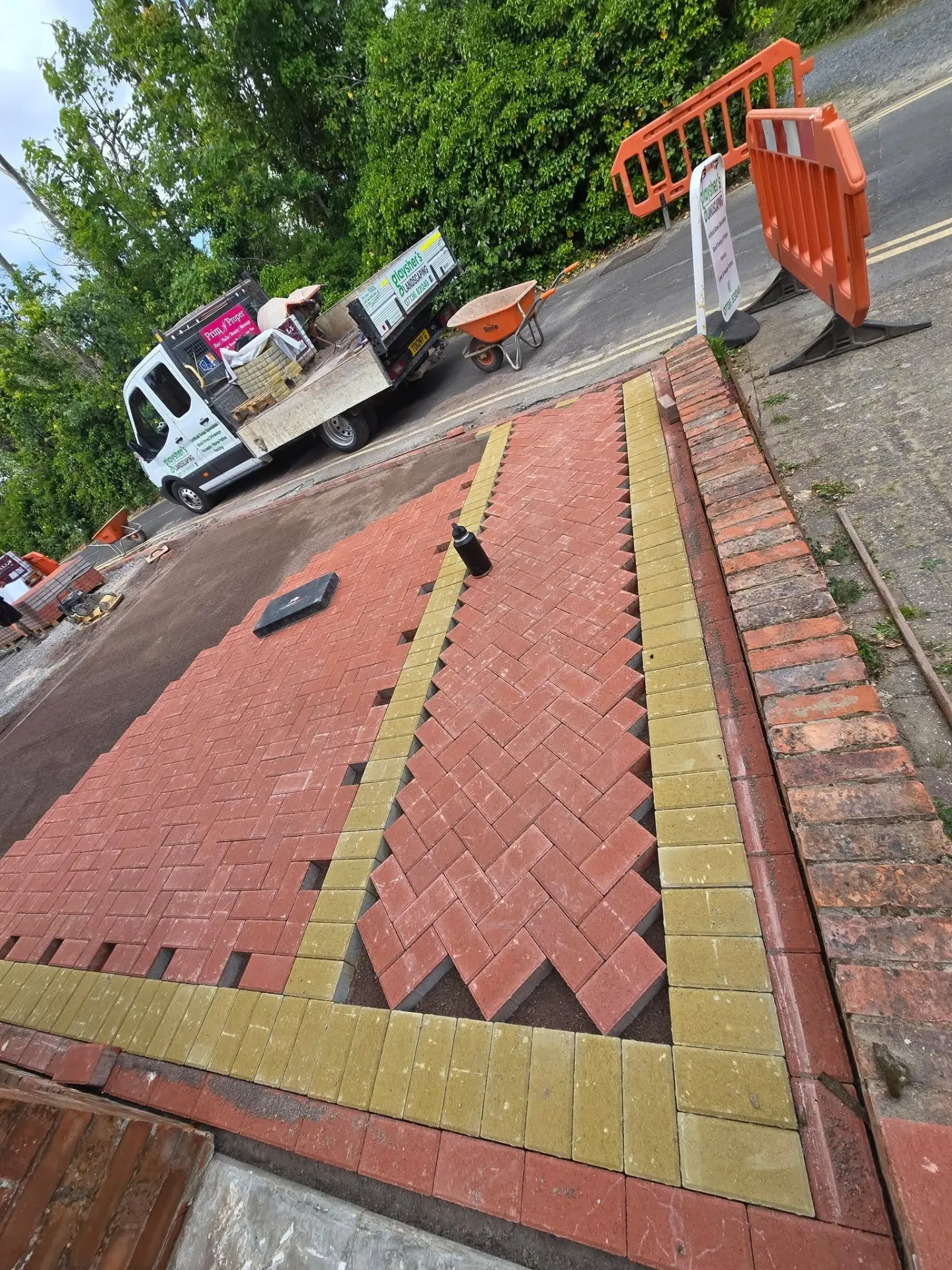 Red block-paved driveway under construction with brickwork borders